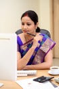 Happy traditional Indian business woman at office desk