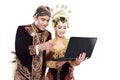 Happy traditional java wedding couple with laptop