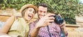 Happy travel couple watching photos on mirrorless camera - Young people having fun on summer vacation - Main focus on him -