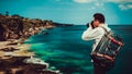 Traveller man backpacker standing on the top mountain cliff on background tropical beach