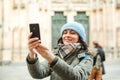 Happy travel woman taking photo with her phone. Autumn or winter trip. Young woman in warm clothes enjoying journey in Europe. Peo