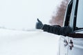 Happy Traveler driving car on snowy road and gesture finger up, man Tourist enjoying snow forest view from the car window in Royalty Free Stock Photo