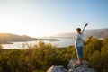 Happy traveler with open arms stands on the rock Royalty Free Stock Photo