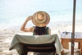 Happy traveler woman in green swimwear and hat enjoy beautiful sea view, young woman sitting on chair at sand beach. Freedom, Royalty Free Stock Photo