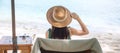 Happy traveler woman in green swimwear and hat enjoy beautiful sea view, young woman sitting on chair at sand beach. Freedom, Royalty Free Stock Photo