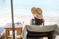 Happy traveler woman in green swimwear and hat enjoy beautiful sea view, young woman sitting on chair at sand beach. Freedom, Royalty Free Stock Photo