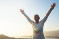 Happy traveler, woman with open arms stands on the rock Royalty Free Stock Photo