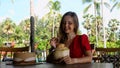 Happy traveler woman relax in cafe with young coconut on beach with palm trees Royalty Free Stock Photo