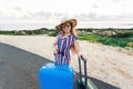 Happy traveler woman with suitcase on the road and laughs. Concept of travel, journey, trip Royalty Free Stock Photo