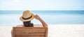 Happy traveler woman in white dress and hat enjoy beautiful sea view, young woman sitting on chair and looking ocean at tropical Royalty Free Stock Photo