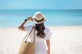 Happy traveler woman in white dress and hat enjoy beautiful sea view, young woman standing on sand and looking ocean at tropical Royalty Free Stock Photo