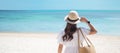 Happy traveler woman in white dress and hat enjoy beautiful sea view, young woman standing on sand and looking ocean at tropical Royalty Free Stock Photo