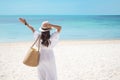 Happy traveler woman in white dress and hat enjoy beautiful sea view, young woman standing on sand and looking ocean at tropical Royalty Free Stock Photo