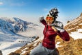 Happy traveler young woman with windy hair smiling, sitting on top of sunny mountains. Funny woman in mohawk hat.