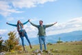 Happy travelers couple conquered top of mountain, raises hands up Royalty Free Stock Photo