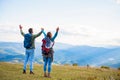 Happy travelers couple conquered top of mountain, raises hands up Royalty Free Stock Photo