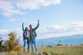 Happy travelers couple conquered top of mountain, raises hands up Royalty Free Stock Photo