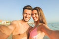 Happy traveling couple making selfie with beach in background - Concept of sunny summer colors and romantic mood - Young people Royalty Free Stock Photo