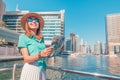 Happy traveller girl with a map on a cruise ship at the Marina port in Dubai. Travel destinations and transport concept