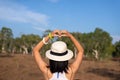 Happy traveller woman standing and showing hands heart shape at nature,Back view