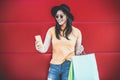 Happy trendy asian girl using shopping app holding bags outdoor - Young woman having fun buying new clothes on web with smartphone