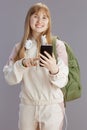 happy trendy school girl in beige tracksuit using phone Royalty Free Stock Photo