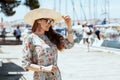 Happy trendy solo traveller woman in floral dress on pier