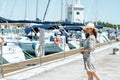 Happy trendy solo traveller woman in floral dress on pier