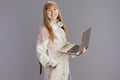 happy trendy teen girl in beige tracksuit using laptop Royalty Free Stock Photo