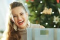 Trendy woman near Christmas tree showing weight scales