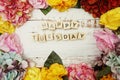 Happy Tuesday alphabet letter with colorful flowers border frame on wooden background