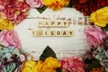 Happy Tuesday alphabet letter with colorful flowers border frame on wooden background