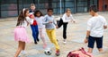 Happy tween girls and boys playing football in schoolyard