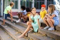Happy tweenagers friends sitting on steps outdoors and chatting