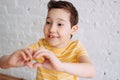 Happy tweens boy in yellow t-shirt making heart by hands on the white wall background Royalty Free Stock Photo