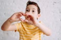 Happy tweens boy in yellow t-shirt making heart by hands on the white wall background, selective focus Royalty Free Stock Photo