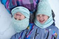 Happy twins children of little sisters girls lying on the snow a