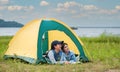 Happy two Asian woman lying down in the tent while camping on meadow near lake in parks and outdoor on vacation
