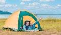 Happy two Asian woman lying down in the tent while camping on meadow near a lake in parks and outdoor on vacation