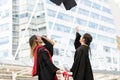 Happy two Asian young beautiful graduate female students with master and bachelor degree throwing cap to the sky after graduation Royalty Free Stock Photo