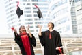 Happy two Asian young beautiful graduate female students with master and bachelor degree throwing cap to the sky after graduation Royalty Free Stock Photo