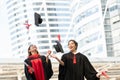 Happy two Asian young beautiful graduate female students with master and bachelor degree throwing cap to the sky after graduation Royalty Free Stock Photo