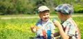 Happy two boys children playing together with toys and blowing soap bubbles in the park on summer day Royalty Free Stock Photo