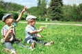 Happy two boys children sitting on grass playing and having fun together outdoors in summer day