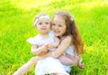 Happy two children sisters on grass in summer