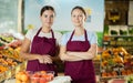 Happy two female sellers wearing apron and standing next to organic foods in supermarket Royalty Free Stock Photo