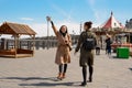 Happy two female students of a friend walk around the city in stylish coats and backpacks and drink coffee from disposable cups, a Royalty Free Stock Photo