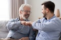 Happy old father and young son laughing giving fist bump