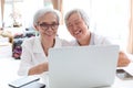 Happy two senior asian woman,sisters or friends talking and enjoying using laptop computer together at home,smiling elderly people Royalty Free Stock Photo