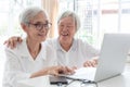 Happy two senior asian woman,sisters or friends talking and enjoying using laptop computer together at home,smiling elderly people Royalty Free Stock Photo